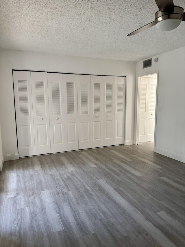 unfurnished bedroom with baseboards, visible vents, a ceiling fan, wood finished floors, and a textured ceiling