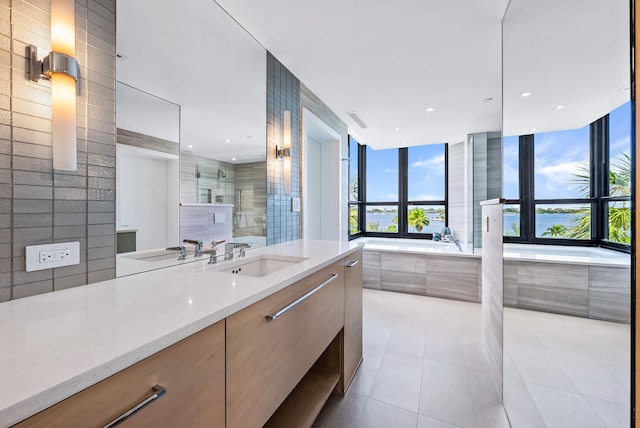 bathroom featuring a tub to relax in, tile patterned floors, vanity, and tile walls