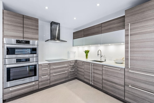 kitchen with black electric stovetop, wall chimney exhaust hood, stainless steel double oven, and sink