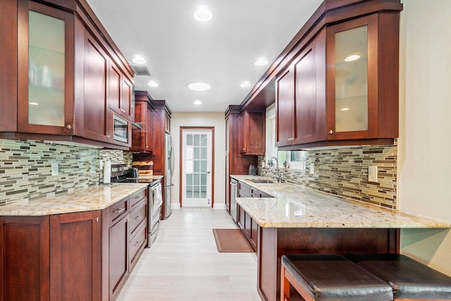 kitchen featuring light stone countertops, appliances with stainless steel finishes, tasteful backsplash, and sink