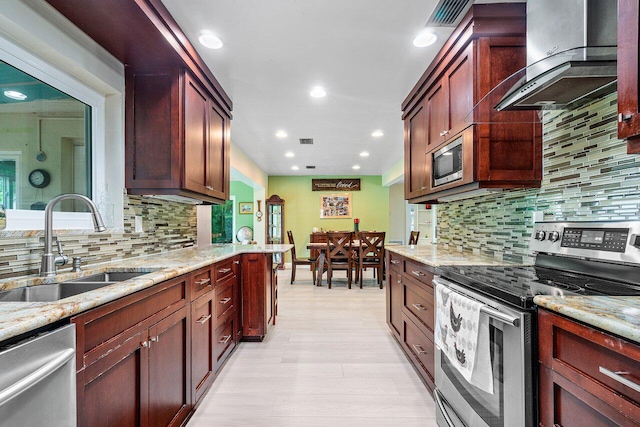 kitchen featuring sink, wall chimney exhaust hood, light stone countertops, appliances with stainless steel finishes, and tasteful backsplash