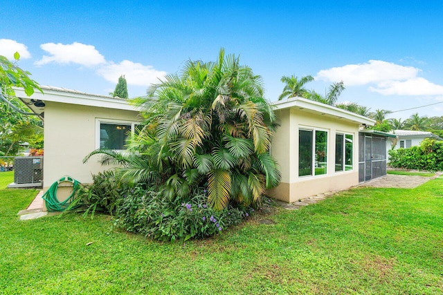 exterior space with a lawn, a sunroom, and cooling unit