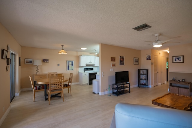 living room with ceiling fan, light wood-type flooring, and a textured ceiling