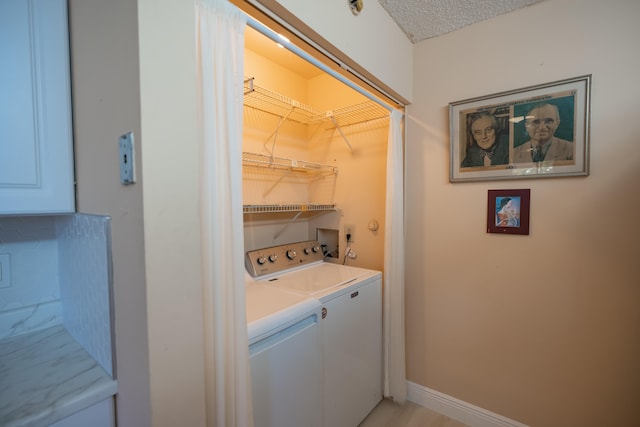 clothes washing area with separate washer and dryer and a textured ceiling