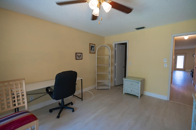 office with a textured ceiling, light wood-type flooring, and ceiling fan