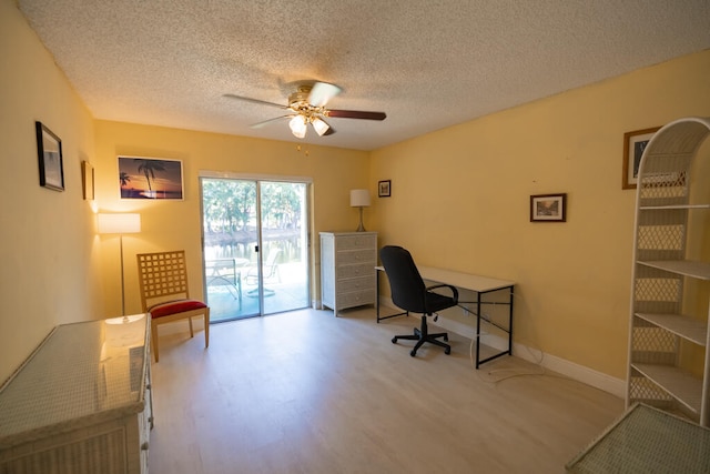 home office featuring ceiling fan, light hardwood / wood-style floors, and a textured ceiling