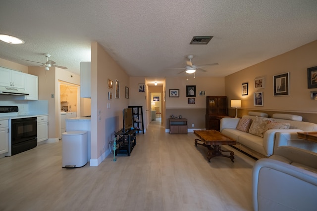 living room with a textured ceiling, light wood-type flooring, and ceiling fan