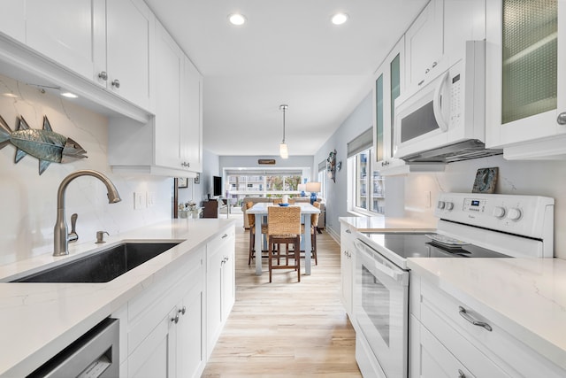 kitchen featuring white cabinets, light wood-type flooring, white appliances, and sink