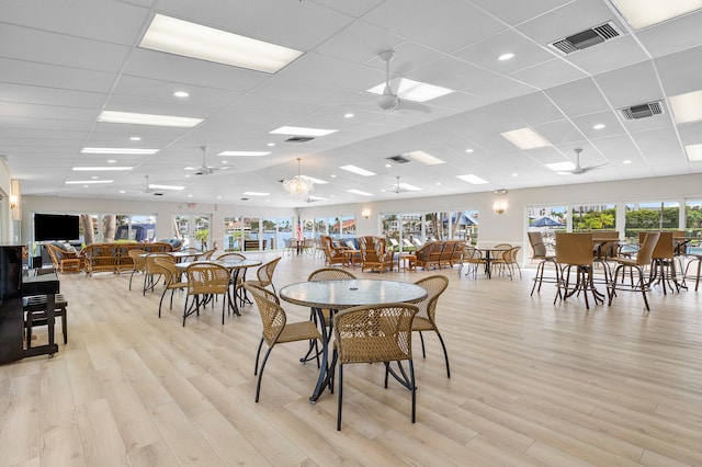 dining area with light hardwood / wood-style flooring, a drop ceiling, and ceiling fan