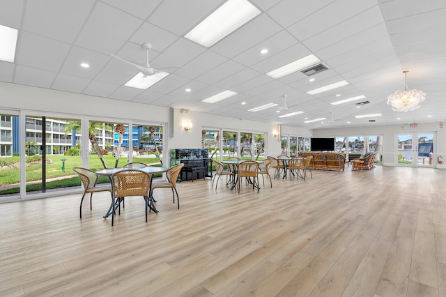 dining space with a wealth of natural light, a drop ceiling, and light wood-type flooring