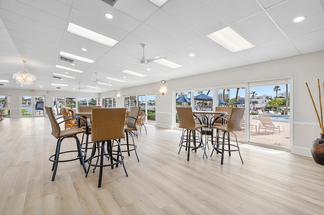 dining space featuring a paneled ceiling, ceiling fan, and light wood-type flooring