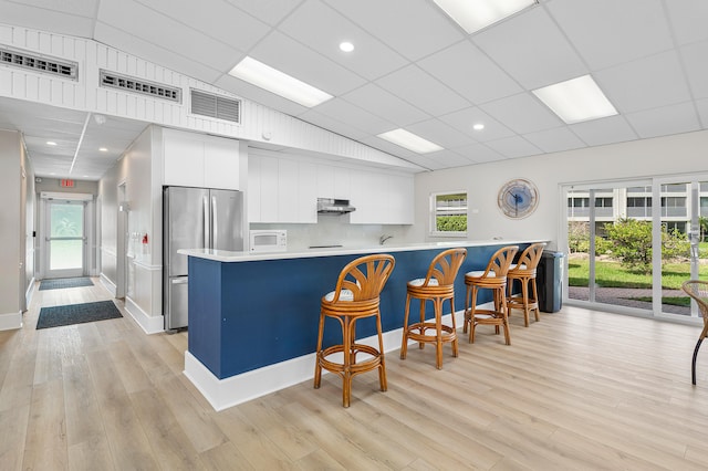 kitchen featuring a healthy amount of sunlight, white cabinetry, and stainless steel refrigerator