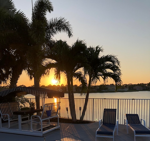 deck at dusk featuring a water view