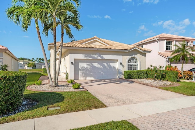 mediterranean / spanish house with a garage and a front lawn