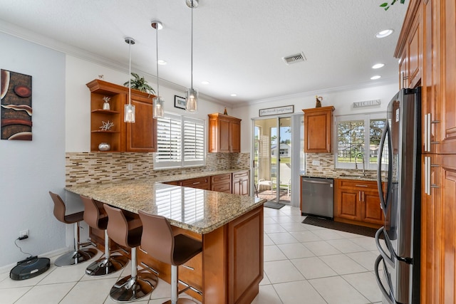 kitchen featuring kitchen peninsula, appliances with stainless steel finishes, decorative light fixtures, and plenty of natural light