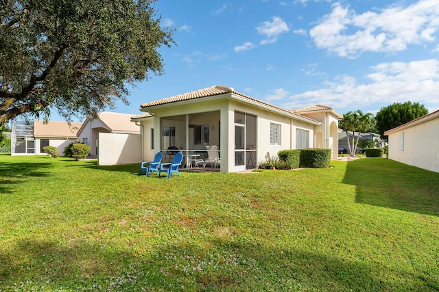 rear view of property featuring a lawn and a sunroom