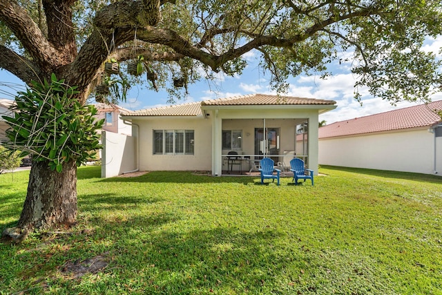 rear view of property with a lawn and a sunroom