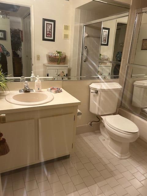 full bathroom featuring tile patterned flooring, vanity, enclosed tub / shower combo, and toilet