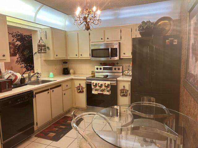 kitchen with sink, an inviting chandelier, cream cabinets, light tile patterned floors, and black appliances