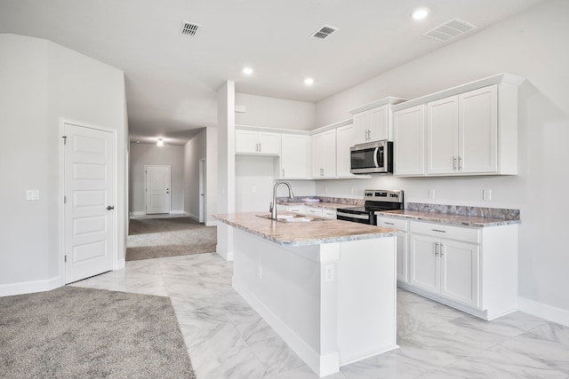 kitchen with sink, white cabinetry, stainless steel appliances, and an island with sink