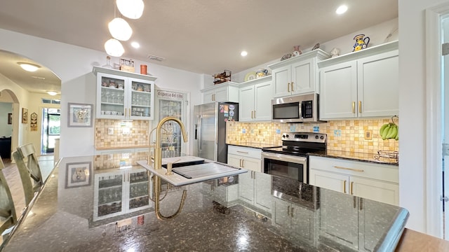 kitchen featuring white cabinetry, sink, tasteful backsplash, dark stone countertops, and appliances with stainless steel finishes