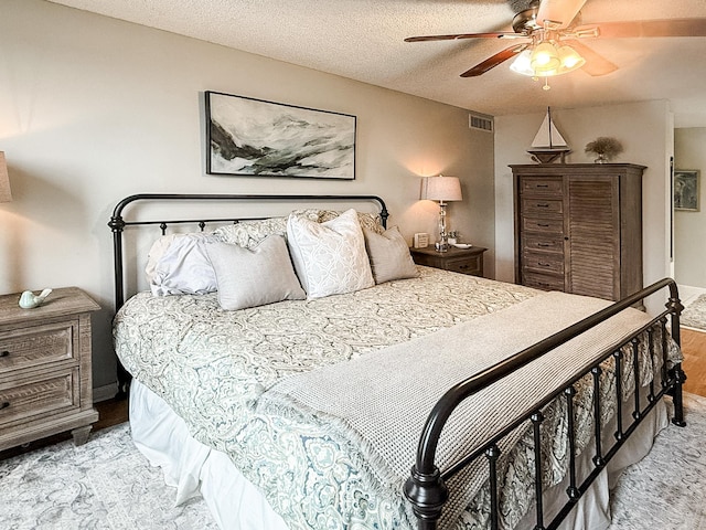 bedroom with ceiling fan, a textured ceiling, and light wood-type flooring