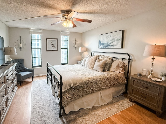 bedroom featuring ceiling fan, a textured ceiling, and light hardwood / wood-style flooring