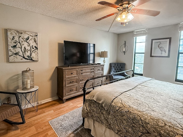 bedroom featuring ceiling fan, light wood-type flooring, and a textured ceiling