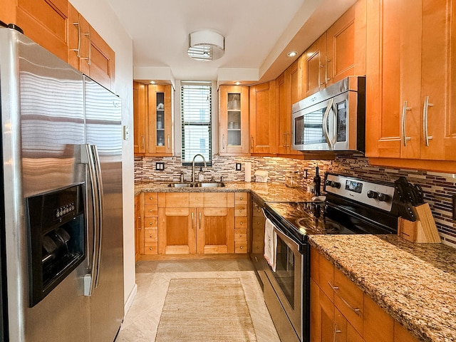 kitchen featuring light stone countertops, appliances with stainless steel finishes, decorative backsplash, sink, and light tile patterned flooring