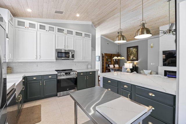 kitchen with pendant lighting, white cabinets, vaulted ceiling, ceiling fan, and stainless steel appliances