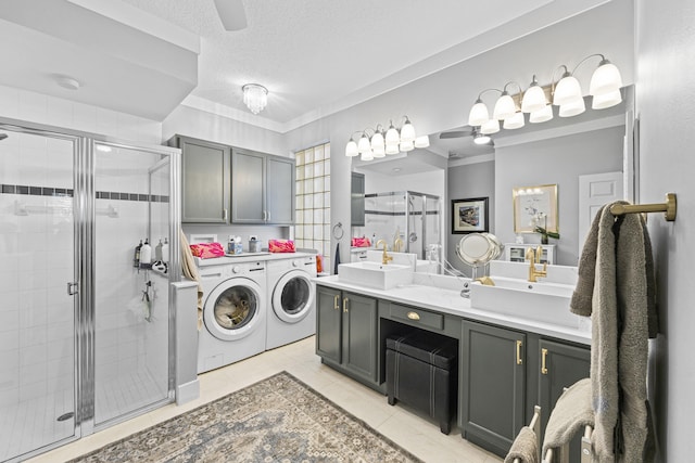 washroom with a textured ceiling, washer and dryer, light tile patterned flooring, and sink