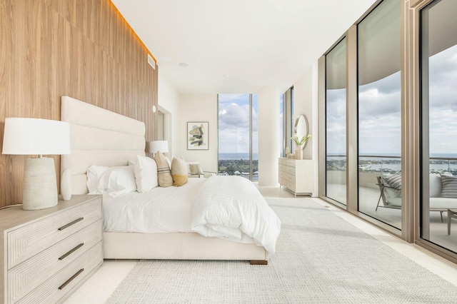 bedroom featuring access to exterior, wood walls, and floor to ceiling windows