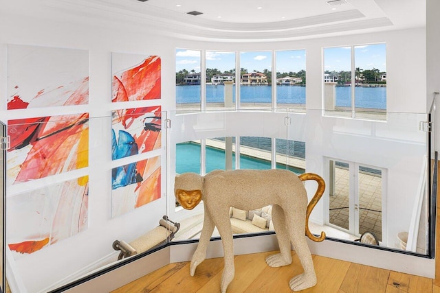 living area with hardwood / wood-style floors, a tray ceiling, and a water view