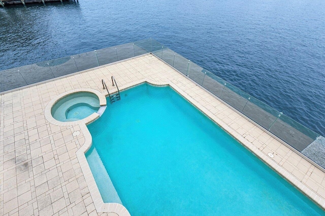 view of swimming pool featuring an in ground hot tub and a water view