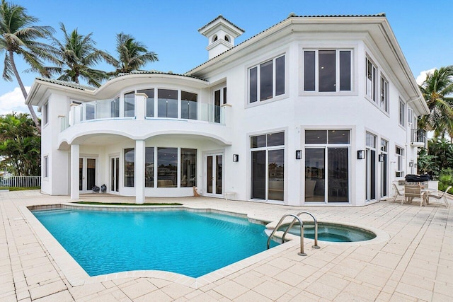 rear view of house featuring french doors, a patio, and a swimming pool with hot tub