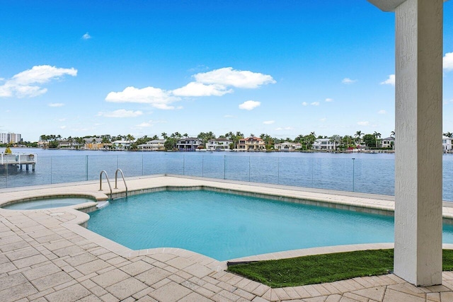 view of swimming pool featuring a water view and an in ground hot tub