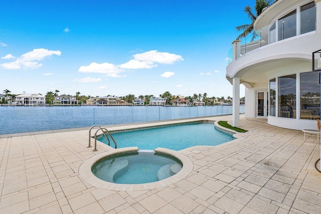 view of pool with a patio area, a water view, and an in ground hot tub