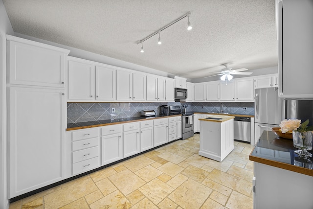 kitchen with white cabinets, appliances with stainless steel finishes, backsplash, and ceiling fan