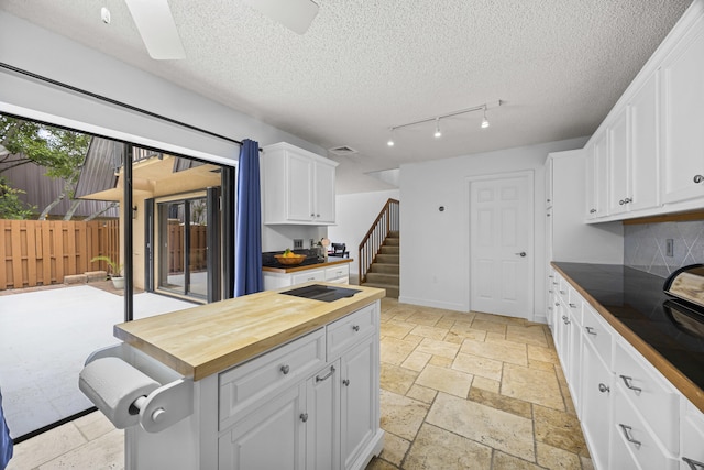 kitchen featuring white cabinetry, ceiling fan, wooden counters, a textured ceiling, and black electric stovetop