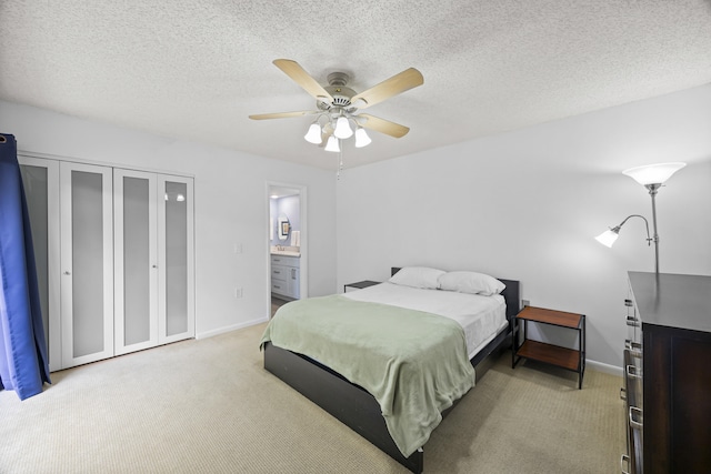 bedroom with light carpet, a textured ceiling, ensuite bath, and ceiling fan