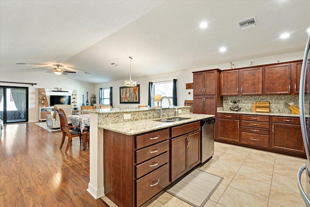 kitchen featuring light wood-type flooring, stainless steel dishwasher, vaulted ceiling, sink, and pendant lighting