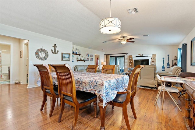 dining space with a textured ceiling, ceiling fan, light hardwood / wood-style floors, and lofted ceiling