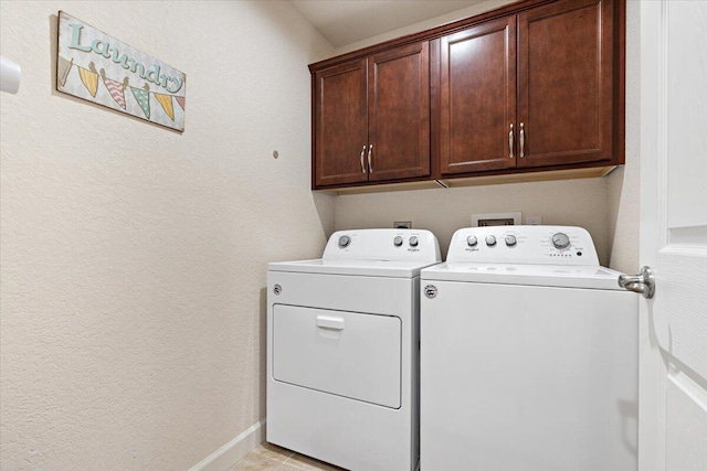 clothes washing area with cabinets, washing machine and dryer, and light tile patterned flooring