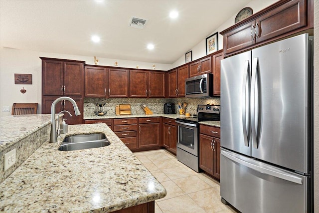 kitchen with lofted ceiling, backsplash, sink, light stone countertops, and stainless steel appliances