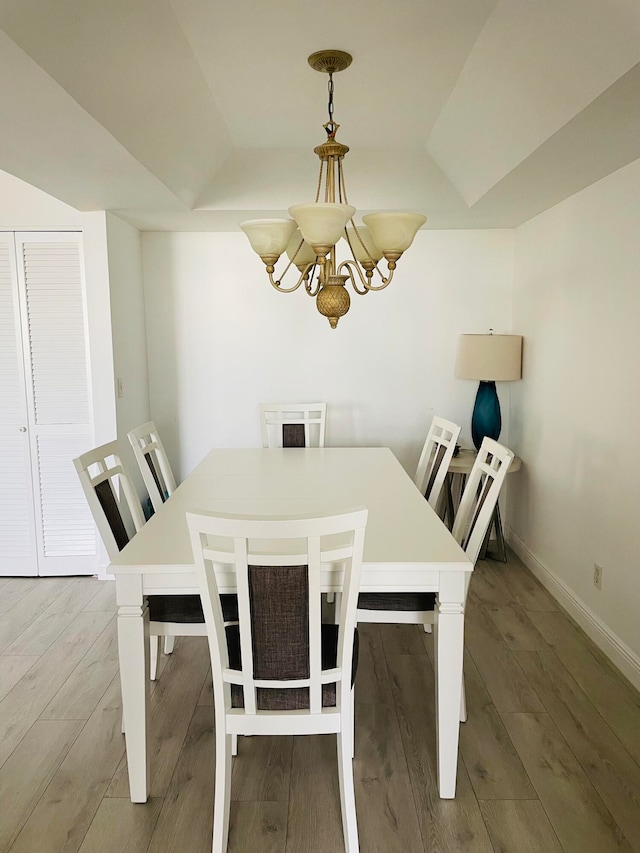 dining room featuring lofted ceiling, a notable chandelier, and hardwood / wood-style flooring