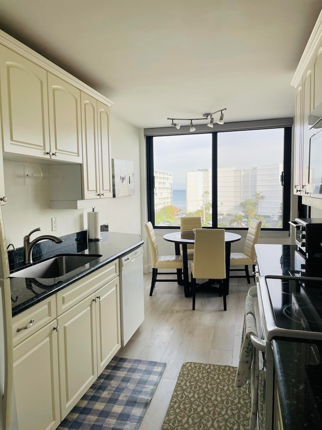 kitchen with cream cabinets, sink, white dishwasher, and light hardwood / wood-style flooring