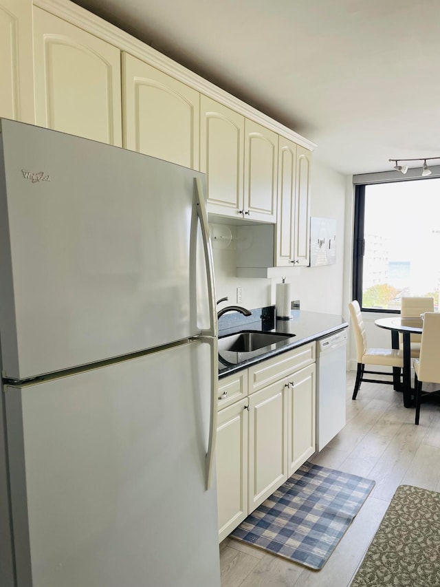 kitchen with light hardwood / wood-style flooring, white appliances, and sink