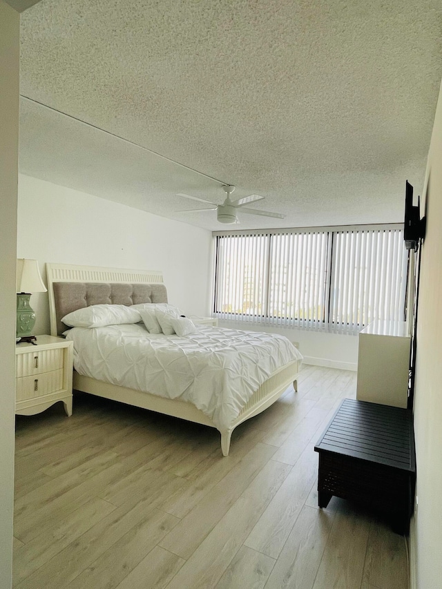 bedroom with ceiling fan, light hardwood / wood-style floors, and a textured ceiling