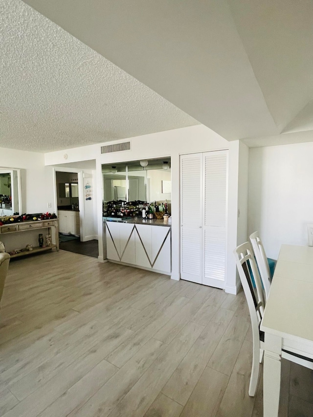 interior space with a textured ceiling and light hardwood / wood-style flooring