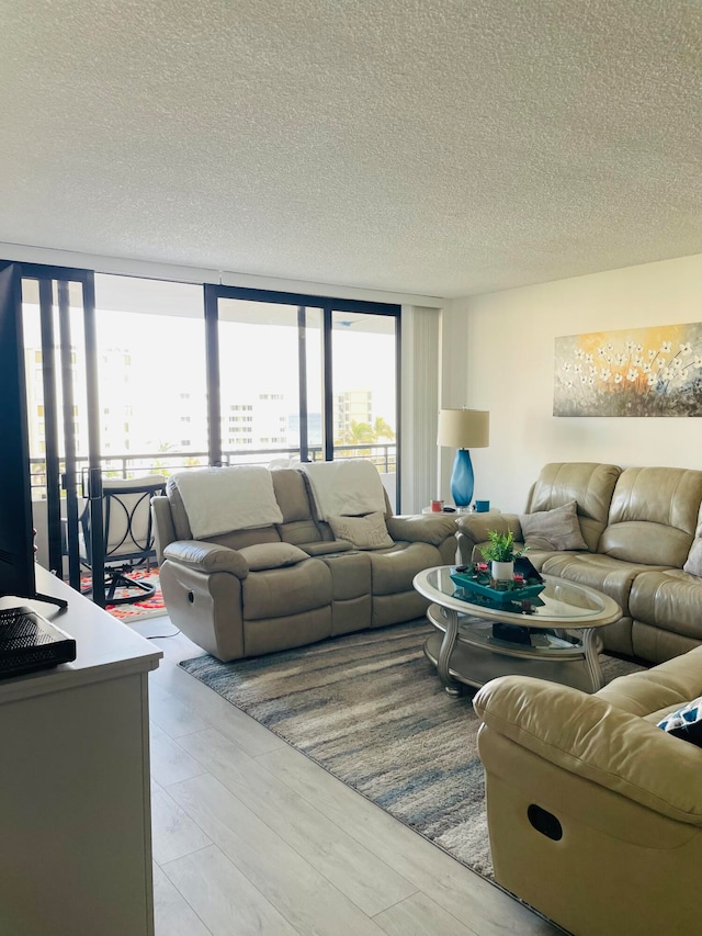 living room featuring a textured ceiling, light hardwood / wood-style floors, and floor to ceiling windows